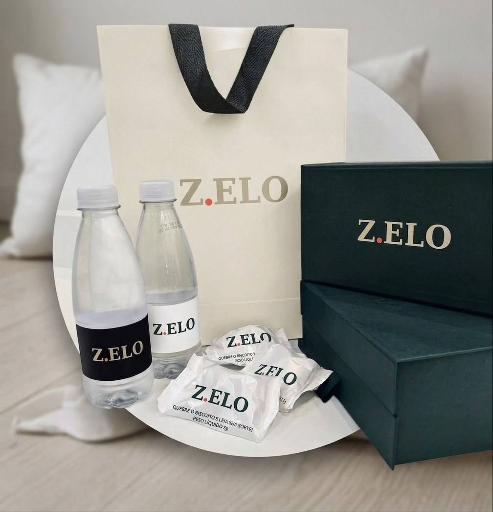 Sacola, caixa, água e biscoitos com a marca Z.ELO, em tons de areia.