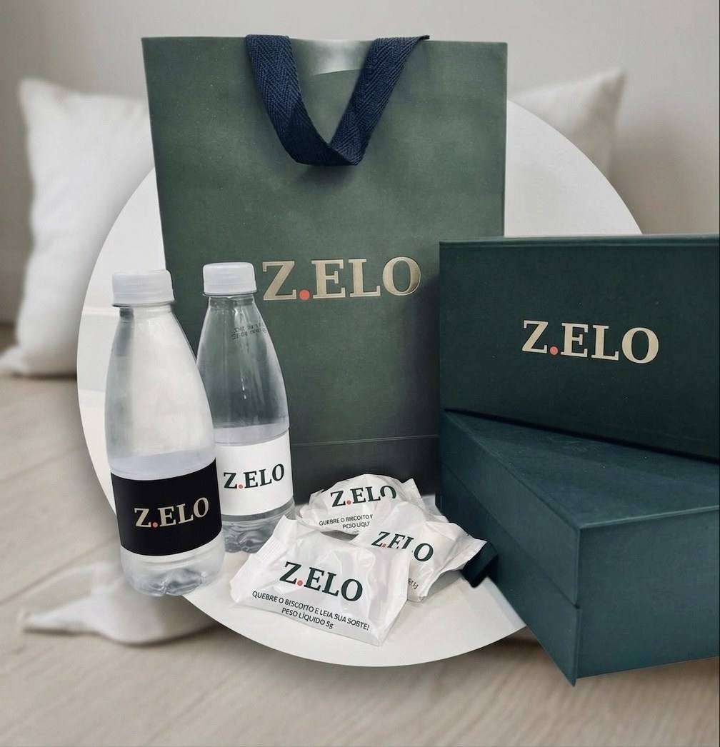 Kit do Protocolo Z.ELO com sacola e caixas verdes, água e biscoitos com a marca.