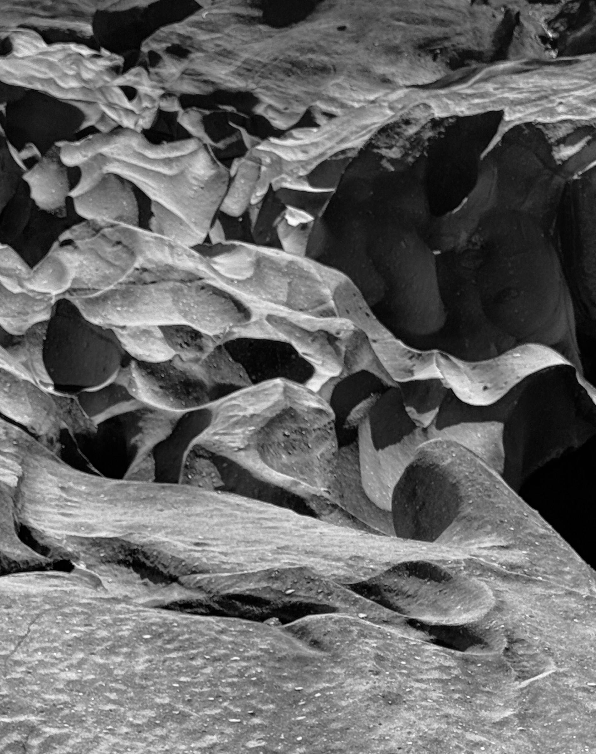 Pedra esculpida lentamente pelo tempo, em preto e branco, como o desgaste silencioso dos dentes.